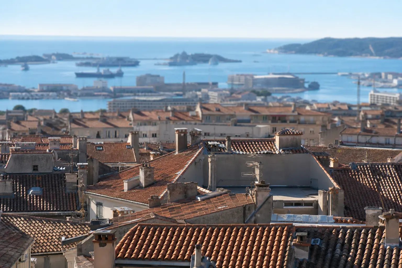 Toits de tuiles du centre ancien de Toulon avec la rade en arrière-plan